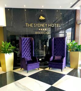 duas cadeiras roxas no átrio de um hotel em The Sydney Hotel em Bolonha