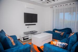 a living room with two blue chairs and a tv at Njakaimba Beachfront Villa. in Mombasa