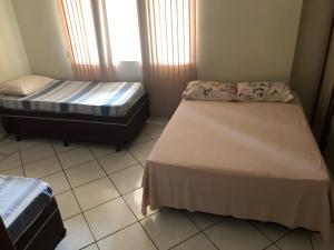 um quarto com 2 camas e piso em azulejo em Hostel Vo Mariana em Goiânia