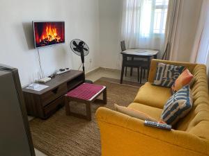 a living room with a yellow couch and a tv at Pacho by Jay in Kisumu
