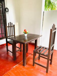 a wooden table with a vase of flowers and a chair at Peacock Villa Resort in Udawalawe