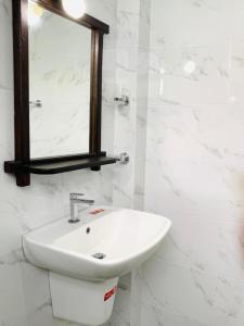 ein weißes Badezimmer mit einem Waschbecken und einem Spiegel in der Unterkunft Peacock Villa Resort in Udawalawe