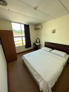 a bedroom with a large white bed with a window at CU Boutique Hotel in Kota Kinabalu