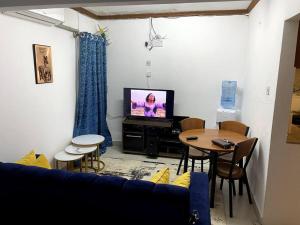 a living room with a couch and a tv and a table at Cottage with AC in Kisumu