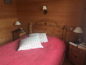 1 dormitorio con 1 cama con edredón rojo y 2 lámparas en crostet du poele en Hauteluce