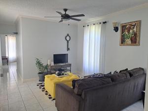 a living room with a couch and a ceiling fan at Ivory Tower Ocho Rios in Ocho Rios