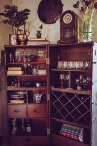 a wooden cabinet with glasses and a clock on the wall at Laethos - the house of fun. in Kfar Yona