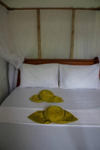 uma cama branca com duas toalhas amarelas em Pamoja Beach Stays Hotel in Jambiani em Jambiani