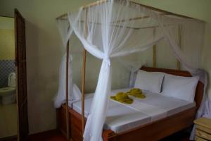 a bedroom with a canopy bed with two yellow towels on it at Pamoja Beach Stays Hotel in Jambiani in Jambiani