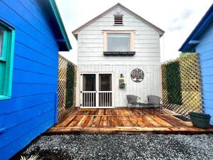 a house with a wooden deck with two chairs on it at Tiny House Hideaway with King Bed in Cape Charles
