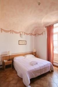 um quarto com uma grande cama branca e uma janela em Hotel Portici em Vicoforte