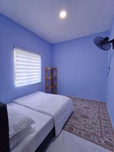 Dormitorio azul con cama y ventana en Singgah Homestay en Kuala Terengganu