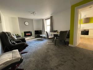 a living room with chairs and a table and a clock at Garden flat in 'Little Chelsea' in Eastbourne