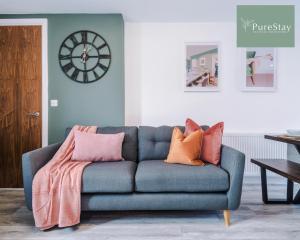 a blue couch in a living room with a clock on the wall at Stunning Five Bedroom House By PureStay Short Lets & Serviced Accommodation Manchester With Free Parking in Manchester