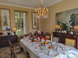 a dining room with a long table with a chandelier at Domaine de Charnay Plaisance Sologne in Vierzon
