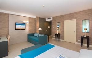 een slaapkamer met een bed en een bank in een kamer bij Hotel Joseph in Marina di Pietrasanta