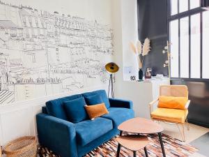 a blue couch in a living room with a drawing on the wall at Montmartre Marvel! Renovated Workshop near the Sacré-Coeur Basilica in Paris