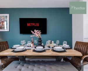 a dining room table with a television on a blue wall at Stylish Five Bedroom House By PureStay Short Lets & Serviced Accommodation Failsworth With Free Parking in Manchester