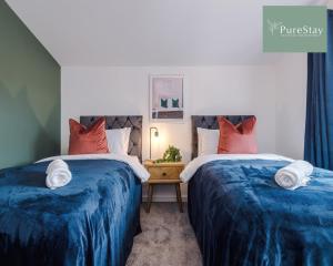 2 Betten in einem Zimmer mit blauen und roten Kissen in der Unterkunft Stylish Five Bedroom House By PureStay Short Lets & Serviced Accommodation Failsworth With Free Parking in Manchester