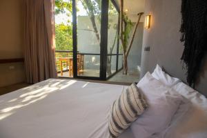 a bed with two pillows in a room with a window at BAU Tulum in Tulum