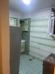 a kitchen with green and white tiled walls and a refrigerator at sea zone in Alexandria