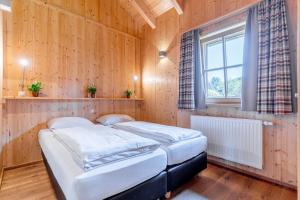 two beds in a room with wooden walls and a window at Feriendorf Oberreit in Maishofen