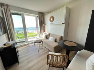 a living room with a couch and a large window at Kaiserhof 311 mit Meerblick - Reinke in Norderney