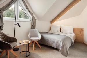 a bedroom with a bed and a chair and a window at Ski & Spa hotel BELLEVUE in Harrachov