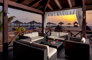 a patio with couches and tables on the beach at Tortuga Beach Villa in Santa Maria