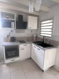 a kitchen with white cabinets and a stove top oven at Villa Sissy: T2 avec jaccuzzi in Sainte-Anne