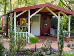 a small red shed with a white door at Ferienwohnung Gulfhaus, mit Sauna und großem Garten in Apen