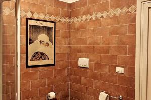 een betegelde badkamer met een ingelijste foto van een vrouw bij Suite Patrimonio Unesco - Assisi Centro Storico in Assisi