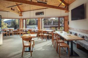 a restaurant with wooden tables and chairs and windows at Ski & Spa hotel BELLEVUE in Harrachov