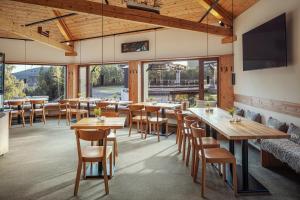 un ristorante con tavoli e sedie in legno e finestre di Ski & Spa hotel BELLEVUE a Harrachov