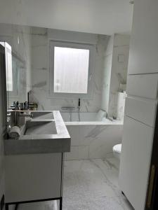 a white bathroom with a sink and a tub and a toilet at Logement proche Stade de France in Saint-Denis