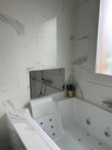 uma casa de banho branca com uma banheira e um espelho. em Logement proche Stade de France em Saint-Denis