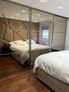 um quarto com 2 camas e um espelho grande em Logement proche Stade de France em Saint-Denis