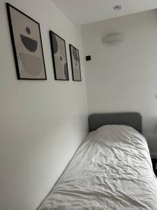 a bed in a bedroom with three pictures on the wall at Logement proche Stade de France in Saint-Denis