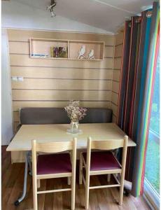 a table with two chairs and a vase of flowers on it at Mobile home proche de EUROPA PARK in Boofzheim