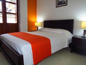 a bedroom with a large bed with a red and white blanket at Hotel Arcadia Colonial in Popayan