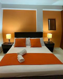 una camera da letto con un grande letto con cuscini arancioni e due lampade di Hotel Arcadia Colonial a Popayan