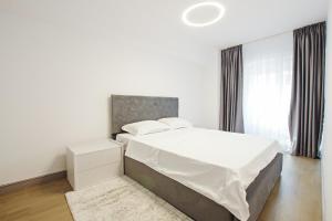 a white bedroom with a large bed and a window at Himson-Brown Apartment in Iaşi