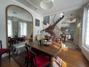a living room with a staircase and a table and a mirror at Maison au calme et au vert au cœur du centre ville in Vincennes
