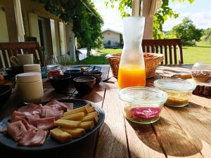 einen Holztisch mit einem Teller Essen und einer Flasche Orangensaft in der Unterkunft Chambre d'hôtes de charme, A Nosté M&P in Poussignac