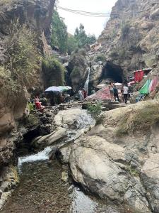 grupa ludzi stojących wokół rzeki z wodospadem w obiekcie Imlil w Marakeszu