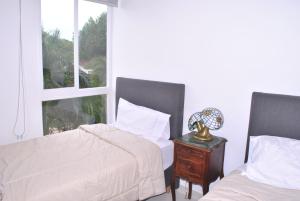 ein Schlafzimmer mit 2 Betten und einem Tisch mit einer Lampe in der Unterkunft Lujoso apartamento frente al mar in Tubará