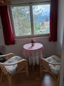 einen Tisch und zwei Stühle mit einem Tisch und einem Fenster in der Unterkunft Ferienwohnung Buddatsch-Hofmann in Oberstdorf