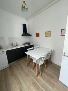 a kitchen with a white table and white chairs at T2 hyper centre avec parking - Entrée Sud in Rodez