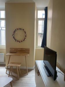 a living room with a tv and a table with a clock at T2 hyper centre avec parking - Entrée Sud in Rodez