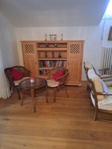 ein Wohnzimmer mit einem Tisch, Stühlen und einem Bücherregal in der Unterkunft Ferienwohnung Buddatsch-Hofmann in Oberstdorf